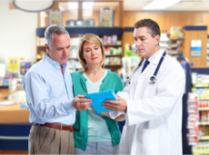 Pharmacist and a senior couple looking at tablet device