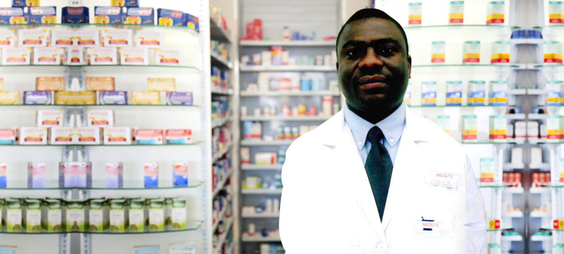 Pharmacist standing in front of pharmacy shelves